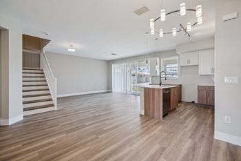 a living room and kitchen with a staircase and a kitchen island at The Falls of Portofino Apartment, Naples, Florida